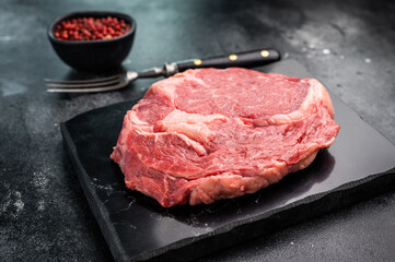Raw Marbled Rib eye steak with spice, dry aged beef meat. black background. top view