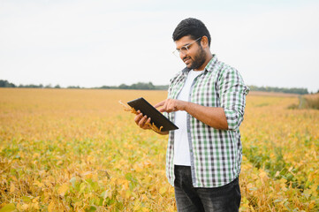 A young Indian farmer works in a soybean field