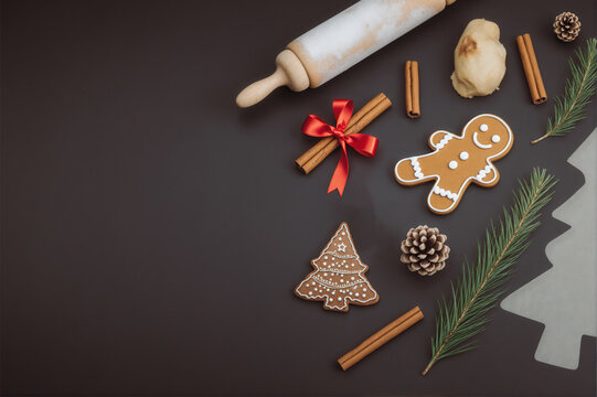 Christmas-themed gingerbread cookies with festive decorations and baking tools on a dark background