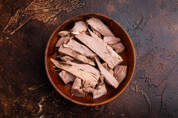 Sustainable tinned tuna fillet in a wooden bowl, promoting eco friendly eating without sacrificing taste. brown background. top view