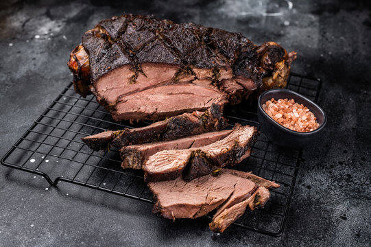 Roasted Roe Deer leg. slow cooked game meat of venison with bone. black background. top view