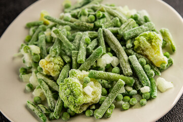 Frozen green vegetables green peas, broccoli, string beans, kohlrabi kale tasty snack fresh food background on the table rustic food top view copy space keto and paleo diet vegan and vegetarian food