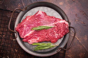 Raw hanger tender beef steak, skirt steak with rosemary on steel tray. brown background. top view