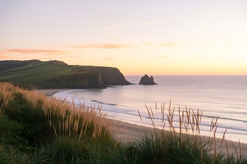 A serene coastal landscape at sunset or sunrise, with gentle waves washing onto a sandy beach and grassy cliffs