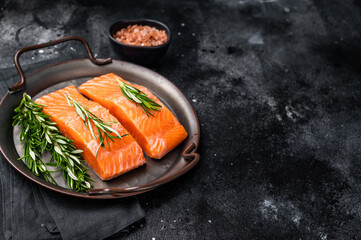 Raw Salmon fillet steak with rosemary ready for cooking. black background. top view