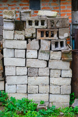 Stacked bricks and concrete blocks near a brick wall in a backyard garden