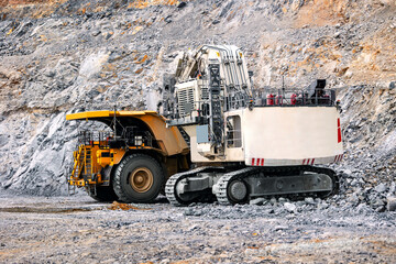 Big yellow mining truck and excavator working at open pit mine