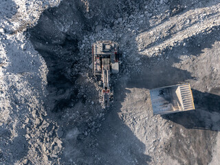 Aerial view of open pit coal mine in winter with excavator and dump truck