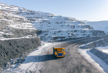 Open pit coal mine in winter landscape with mining truck, sunlight