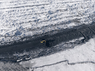 Aerial view of winter open pit coal mine with snow-covered terrain