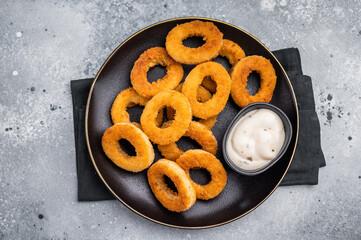 Fried squid rings, calamari seafood snack in a plate with deep. grey background. top view