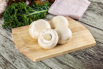 White champignon mushrooms heap over board