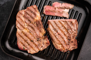 Fried on grill skillet pork tender steak, neck meat. black background. top view