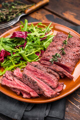 Grilled Skirt machete beef steak, roasted sliced meat on plate with salad. wooden background. top...