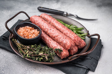 Raw Cevapcici ready for the grill, fresh Cevapi from mince beef meat. grey background. top view
