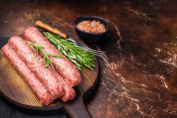 Fresh raw beef and lamb meat kebabs sausages  on wooden board. brown background. top view