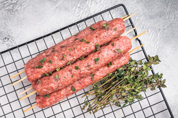 Raw kofta or lula kebabs skewers from mince lamb and beef meat on Skewer. grey background. top view