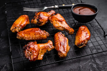 Mouthwatering BBQ chicken wings, coated in a rich sauce, perfect for finger-licking appetizers at any gathering. black background. top view