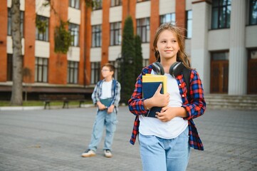 Cute girl reading a book near school. A child in the schoolyard during recess reads a school...