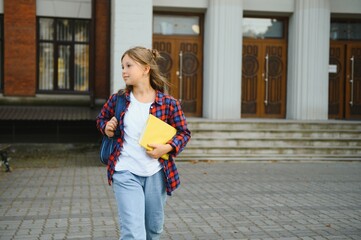 Portrait of a schoolgirl with a backpack on a school background