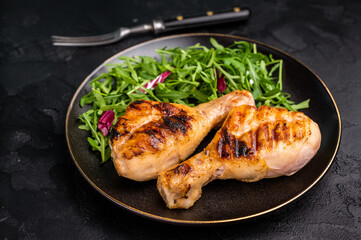 Deliciously grilled chicken legs drumsticks, featuring a crispy skin and juicy meat, a must have for any outdoor feast. black background. top view