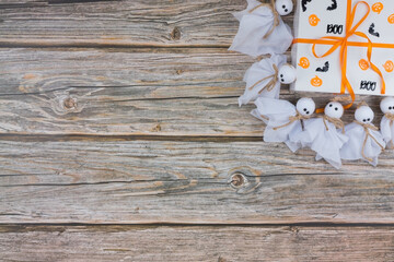 Helloween Gift Box with Decorations and Ghosts on Wooden Background, top view, copy space