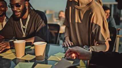 Three stylish afro american young adults collaborating outdoors on rooftop at golden hour, smiling and focused on laptop. - Powered by Adobe