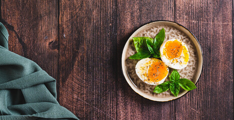 Spicy soft-boiled egg halves and basil on a plate on a table top view web banner