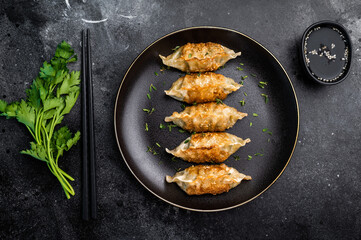 Fried Japanese Gyoza Dumplings with meat and vegetables on plate. black background. top view