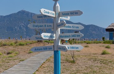 A signpost with distances to several cities is near a path on Turtle Beach - Dalyan Delta - Dalyan - Mugla - Turkey