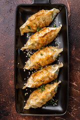 Fried Jiaozi on plate with sauce, Chinese Dumplings with shrimps and vegetables. brown background. top view