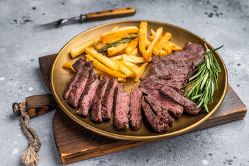 BBQ Grilled Beef Skirt Machete Steak on a plate with french fries grey background. top view