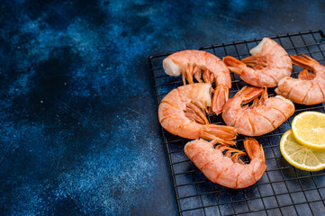 Ready for cooking Headless Red shrimps, raw Prawns on a rack. blue background. top view
