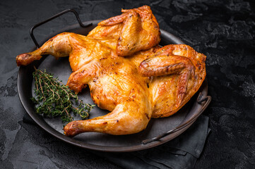 Roasted chicken Tabaka with herbs and spices, poultry meat on steel tray. black background. top view