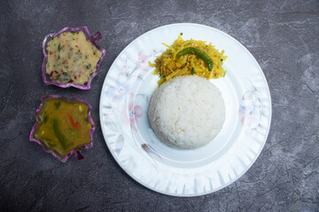 Traditional vegetarian meal with rice, aloo bhorta, fried potato bhaji, and dal curry in plate top...