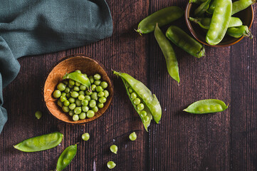 Fresh green peas in a bowl and in pods on the table top view