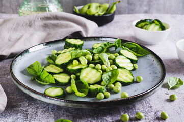Antioxidant salad of fresh cucumbers, green peas and basil on a plate on the table