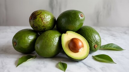 Pile of fresh avocados with one halved on marble surface