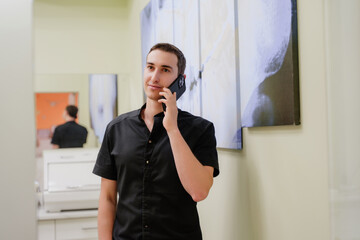 The doctor is talking on the phone. A dentist in a black uniform looks at the camera and smiles. A...