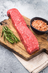 Juicy raw Kobe style beef, renowned for its exceptional flavor and tenderness. Perfect for preparing mouthwatering steaks or sashimi. grey background. top view
