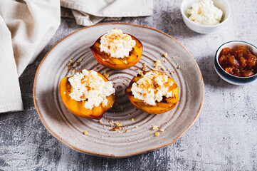 Grilled peaches with cottage cheese, nuts and honey on a plate on the table