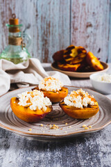 Grilled peach halves with ricotta and nuts on a plate on the table vertical view