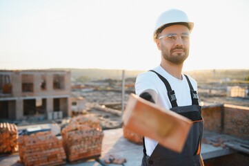 Installing brick wall. Construction worker in uniform and safety equipment have job on building