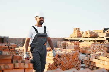 Portrait of an Indian construction worker in overalls and a hard hat at a construction site