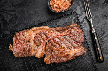 BBQ grilled Chuck eye roll steak, prime beef meat on a steel rack. black background. top view