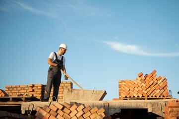 Man bricklayer installing bricks on construction site