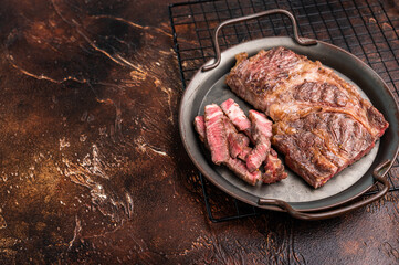BBQ fried and sliced Chuck eye roll steak in a steel tray, prime beef meat. brown background. top view