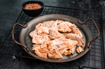 Roast salmon fillet, pulled fish meat on a steel tray. black background. Top view