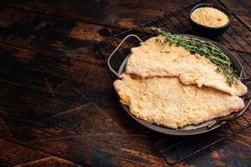 Viennese breaded raw Schnitzel steak on a tray. wooden background. top view