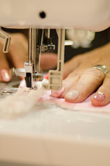 Seamstress weaving pink fabric with sewing machine